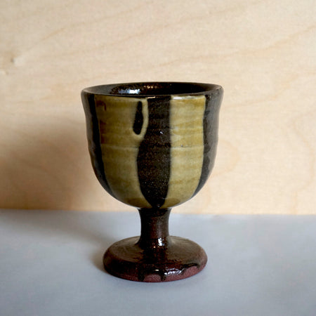 a stoneware wine goblet with light green lines in the glaze. 