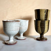 four ceramic wine goblets on a table. 