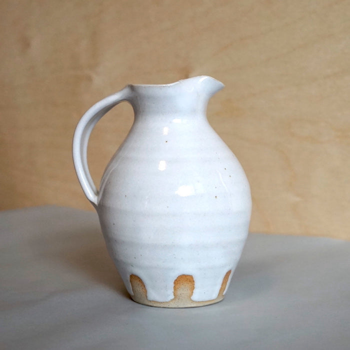 a white milk jug with a bellied shape by Lily Pearmain. 