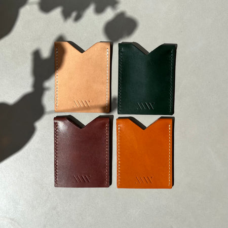 4 leather card holders on a blue table in the sun. 