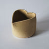 a honey coloured handmade ceramic cup in the shape of a heart by Mae Ceramics. 