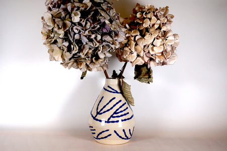 bunch of dried hydrangeas in a porcelain vase with a hand painted blue pattern.  