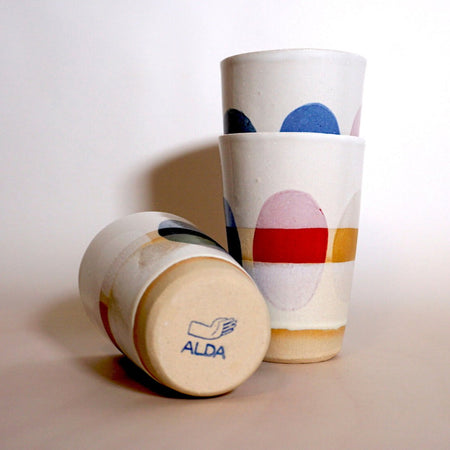 three cups with multi coloured dots painted around the side. one is lying down to show the makers mark of Sophie Alda. 