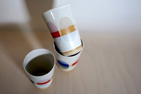 three cups with multi coloured dots painted around the side. 