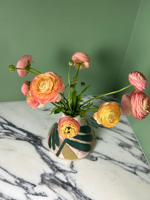 a bunch of pinky yellow flowers in a hand painted vase. 