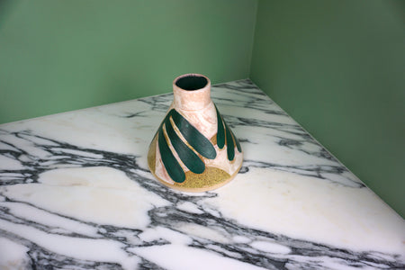 cone shaped vase with a leaf pattern on a marble table with a green background. 