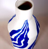 the neck of a porcelain white bottle vase with a bright blue leaf pattern. 