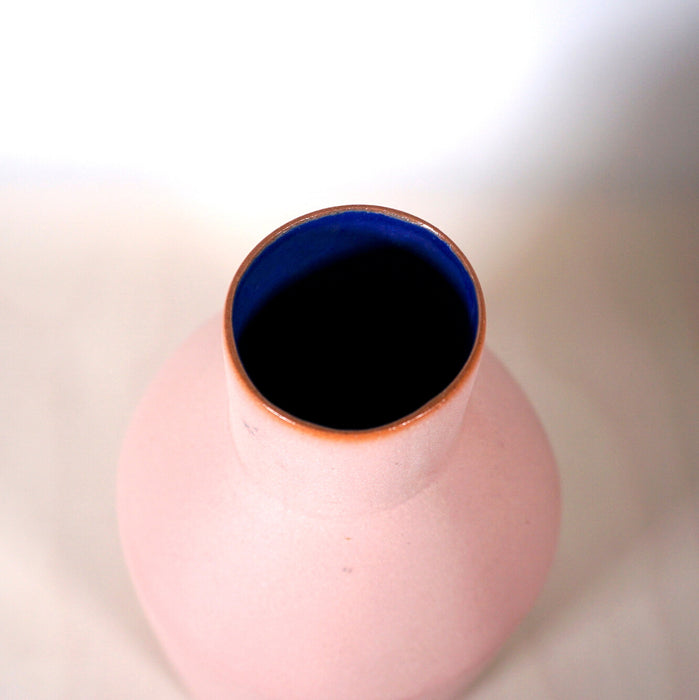 the top of a pink vase with a bright blue interior. 