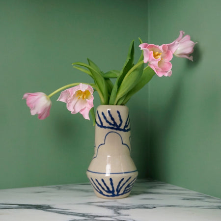 the back of a hand painted ceramic vase with a bunch of pink tulips. 