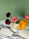 a bunch of flowers in an oatmeal vase on a marble table. 