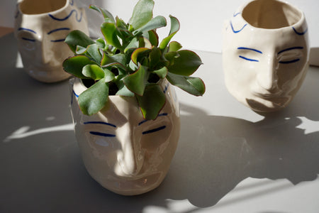 a planter in the shape of a head with hand painted blue pattern. 