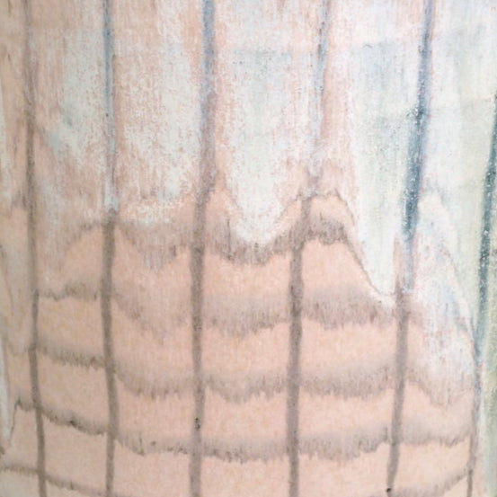 handmade jug with a crosshatch pattern and yellow handle on a marble table with a green background. 