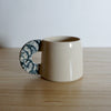 cream coloured stoneware espresso cup with a navy splodge handle. 