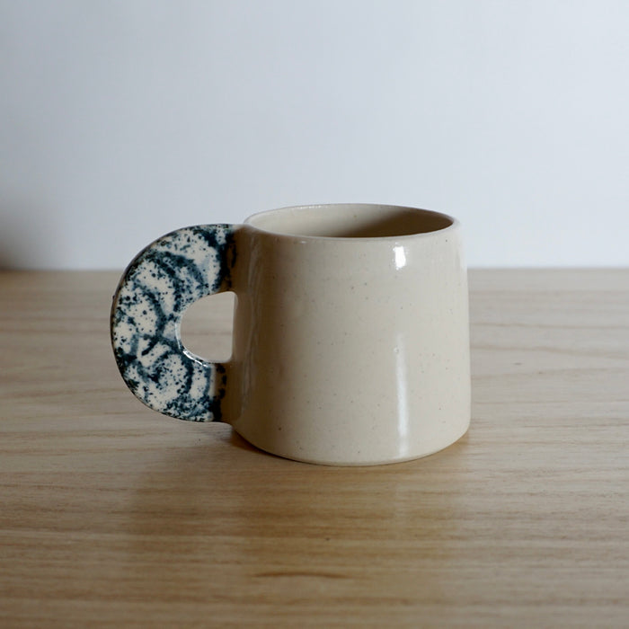 cream coloured stoneware espresso cup with a navy splodge handle. 