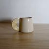 handmade cream coloured espresso cup with a yellow handle. 