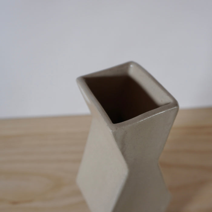 detail of the opening of a simple cream coloured handmade vase. 