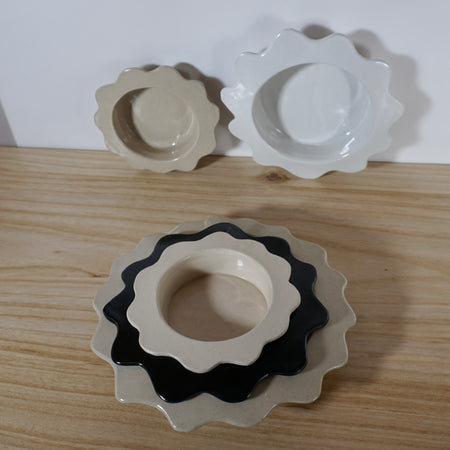 five serving bowls - three stacked and two leaning against a wall. 