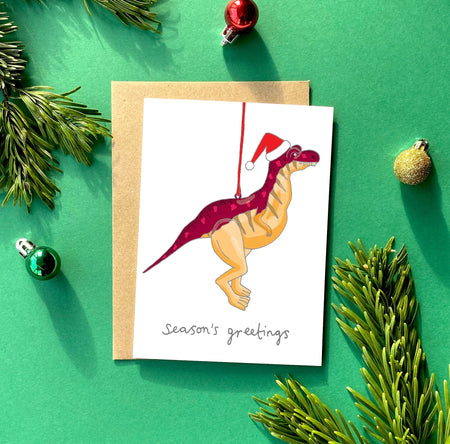 Christmas card with a hanging dinosaur ornament. 