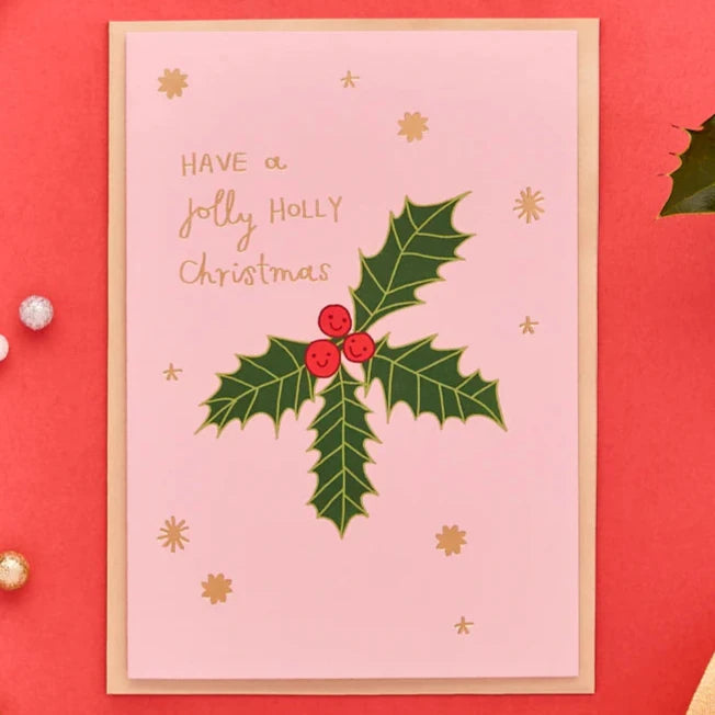 an illustrated christmas card with a bunch of holly and gold lettering that reads have a jolly holly christmas. 