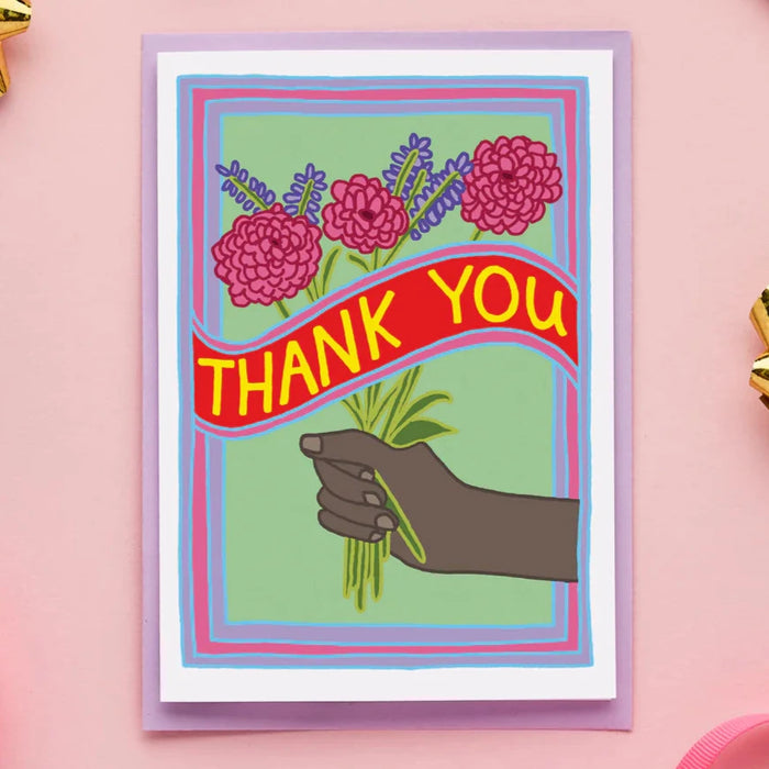 a card with an illustration of a hand holding a bunch of flowers and a banner that says thank you. 