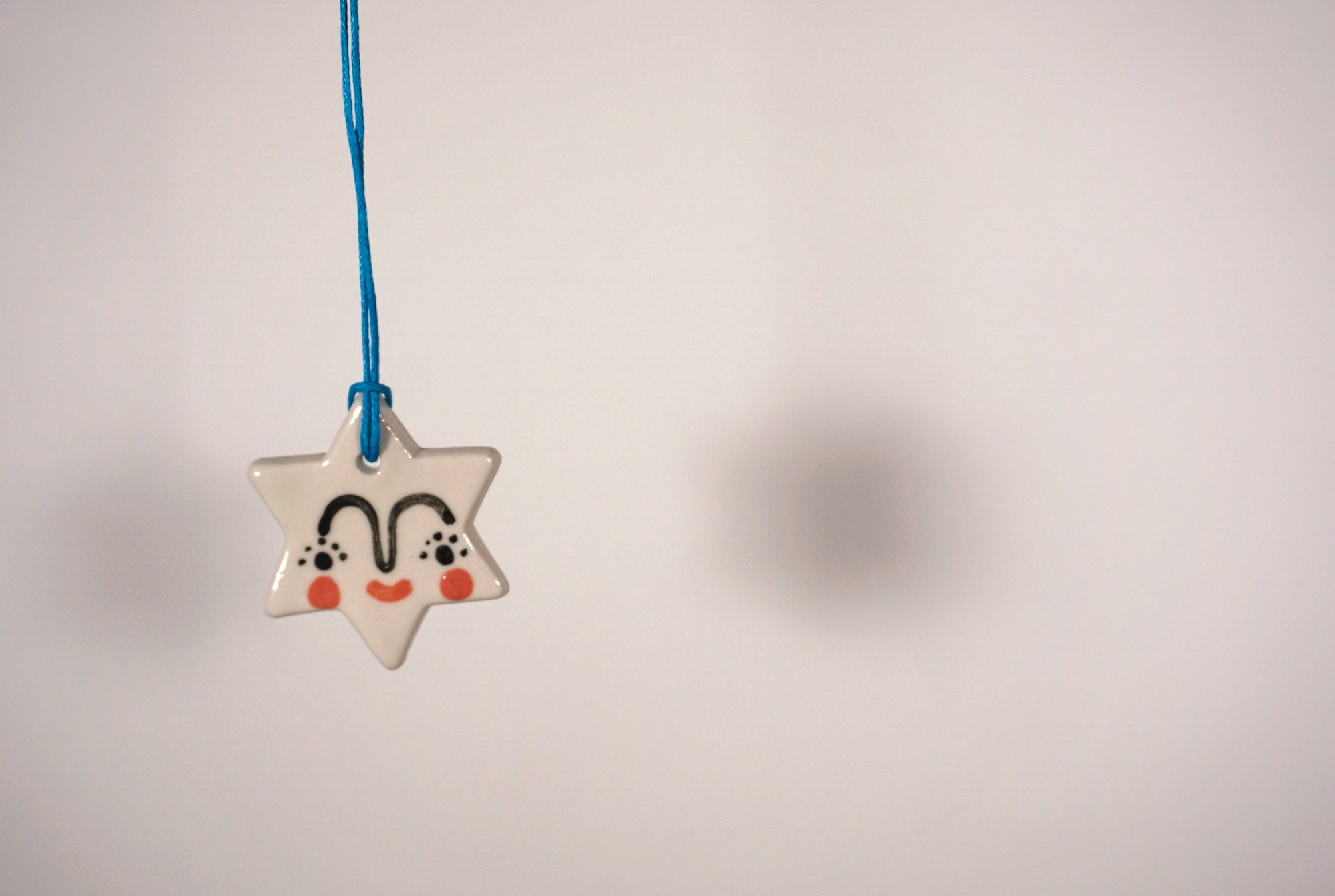 christmas star tree decoration hanging up on a light coloured background. 