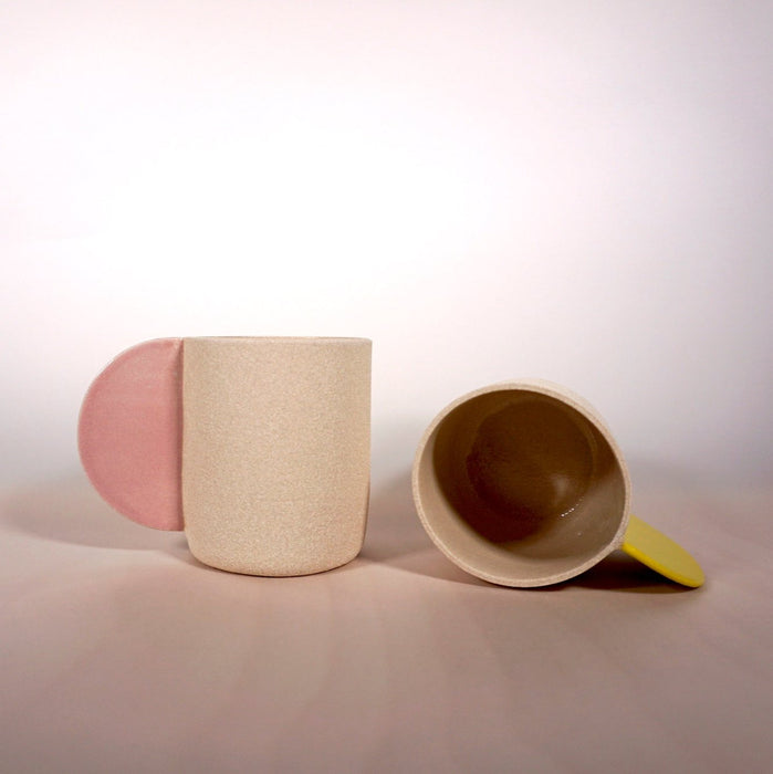 two sand coloured mugs. one is on its side so you can see into the mug. 