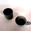 two espresso cups in different shades of grey on a light background. 