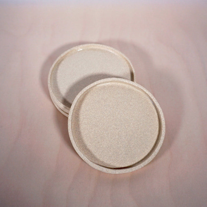 light coloured saucers in a stack with the top one at an angle. 