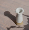 a white Cara Guthrie candlestick holder in bright sunshine with a long shadow. 