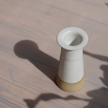 a white Cara Guthrie candlestick holder in bright sunshine with a long shadow. 