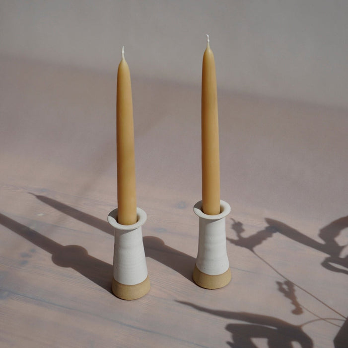 two white glazed stoneware candlestick holders with UK beeswax candles. 