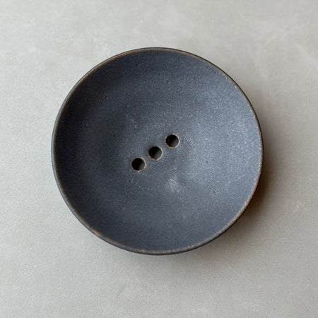 a dark charcoal round soap dish. 