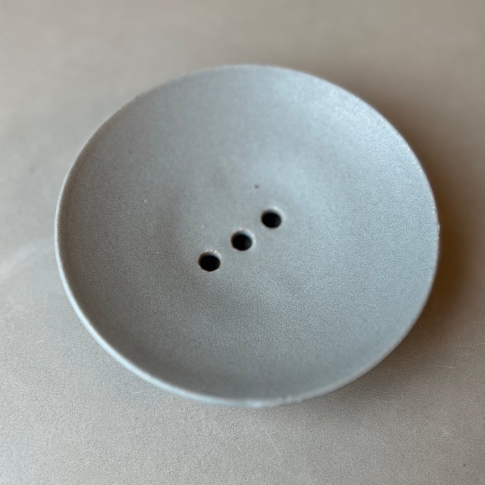 a duck egg blue ceramic soap dish with three drainage holes. 