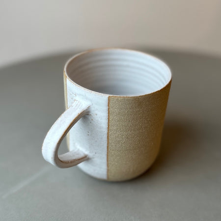 a stoneware mug with a white glaze on the inside and also in a stripe over the handle. 