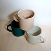 a pyramid of three mugs on a wooden surface. 