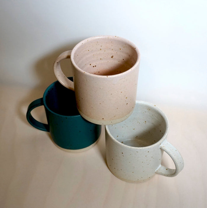 a pyramid of three mugs on a wooden surface. 